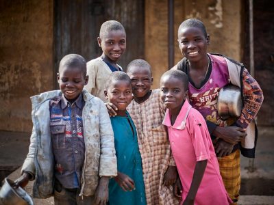 A joyful group of children smiling and posing outside, portraying diversity and friendship.