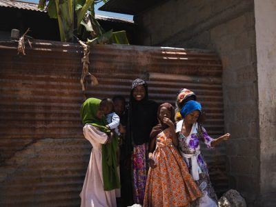 A family enjoys a sunny day together in Zanzibar, showcasing cultural attire and happiness.